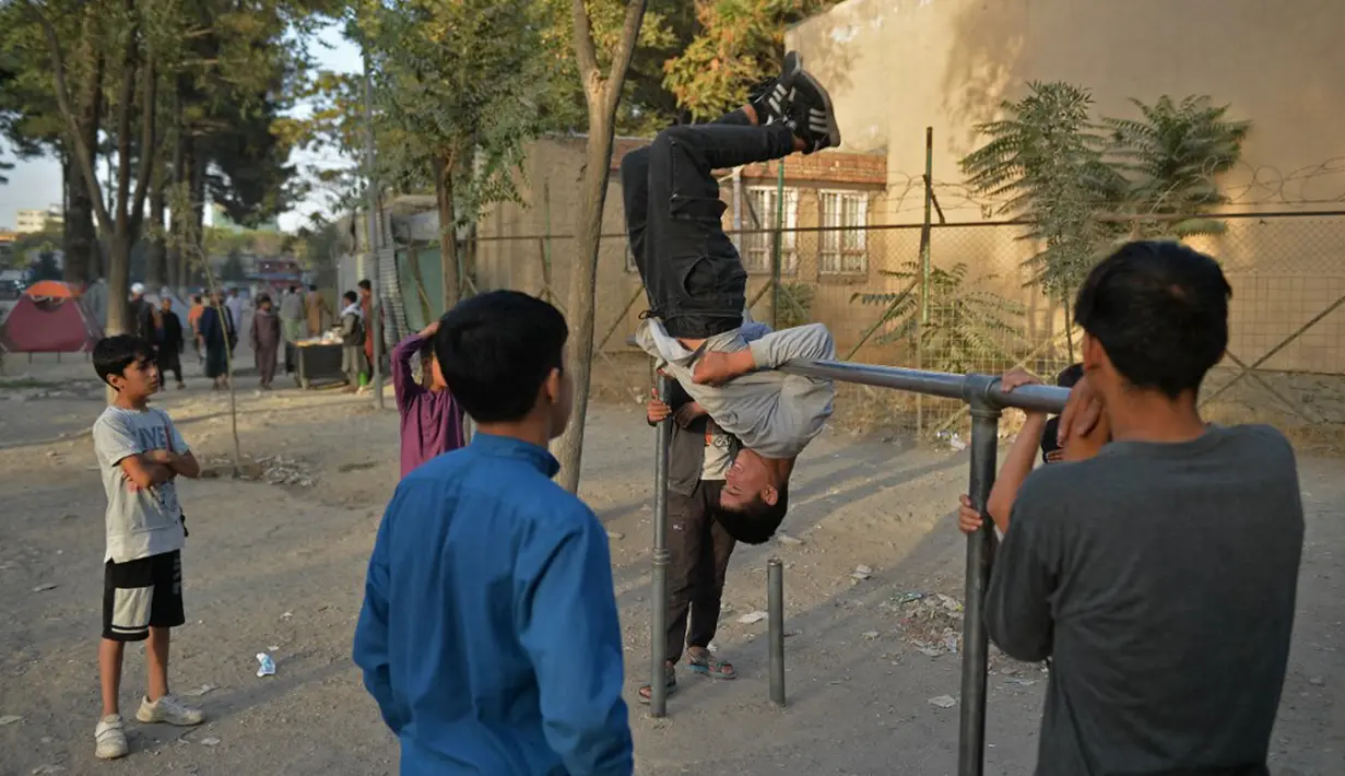 Anak-anak bermain pada palang besi yang terpasang di Shahr-e Naw Park, Kabul, Afghanistan, 9 September 2021. Taliban menguasai Afghanistan setelah pasukan Amerika Serikat meninggalkan negara tersebut. (HOSHANG HASHIMI/AFP)