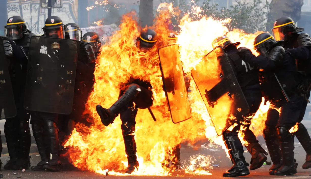 Seorang perwira polisi Prancis terbakar dalam bentrokan dengan pengunjuk rasa perayaan May Day di Paris, Senin (1/5). Satu polisi mengalami luka bakar serius dan dua lainnya luka-luka dalam bentrokan yang melibatkan bom molotov. (Zakaria ABDELKAFI/AFP)