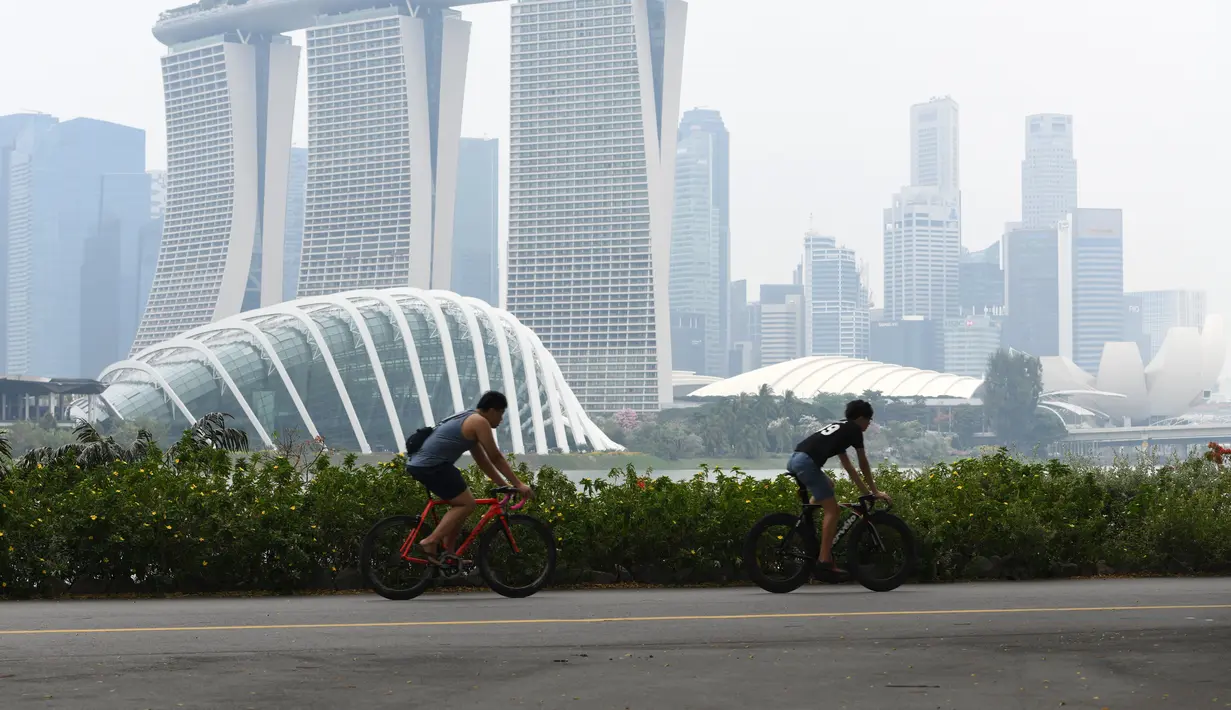Warga beraktivitas saat kabut asap menyelimuti kota Singapura (15/9/2019). Akibat kabut asap yang terjadi di kota tersebut membuat Grand Prix Formula 1 di Singapura pekan depan, 20-22 September 2019, terancam batal.  (AFP Photo/Roslan Rahman)