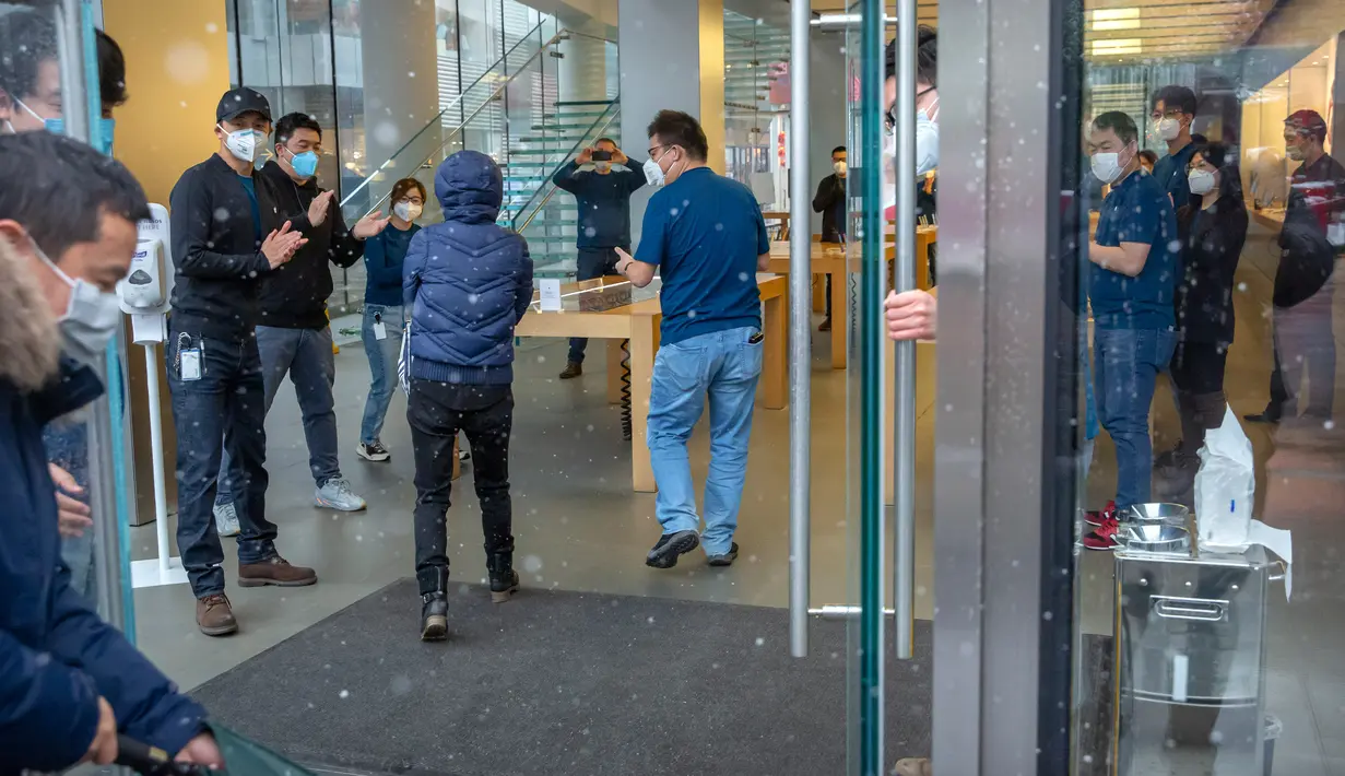 Pekerja bertepuk tangan saat pelanggan memasuki Apple Store yang dibuka kembali di Beijing, China, Jumat (14/2/2020). Pelanggan yang yang akan memasuki toko diminta menggunakan masker dan mau mengikuti pengecekan suhu tubuh. (AP Photo/Mark Schiefelbein)