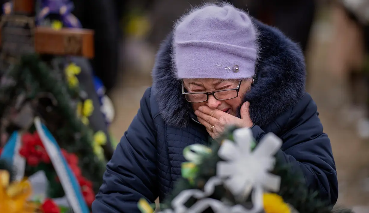 Maria Kurbet, 77 tahun, menangis di makam putranya, seorang prajurit militer yang gugur di Bakhmut, saat upacara peringatan satu tahun dimulainya perang Rusia-Ukraina, di sebuah pemakaman di Bucha, Ukraina, Jumat, 24 Februari 2023. (AP Photo/Emilio Morenatti)