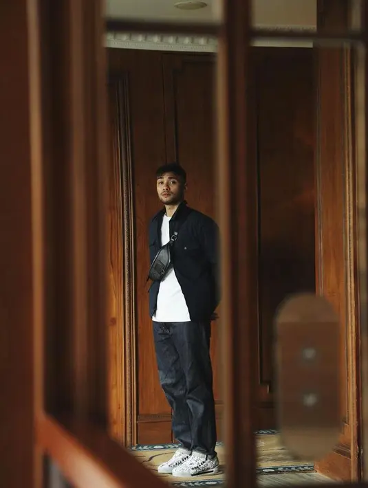 Tampil kece dengan outfit monokrom. Padukan jaket warna hitam, kaos pitih sebagai dalaman, dan celana hitam. Lengkapi penampilanmu dengan waist bag yang kece. (Instagram/refalhady).