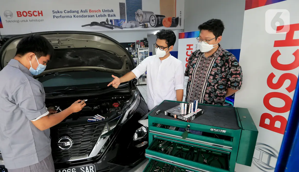 Channel Marketing Manager Bosch Automotive Aftermarket Indonesia, Arditya Wicaktama (tengah) dan perwakilan Sumber Berkat Group selaku distributor komponen mobil (kanan) berbincang dengan mekanik saat pemasangan busi di bengkel Kemayoran, Jakarta, Sabtu (23/01/2022).  (Liputan.com/HO/Astro)