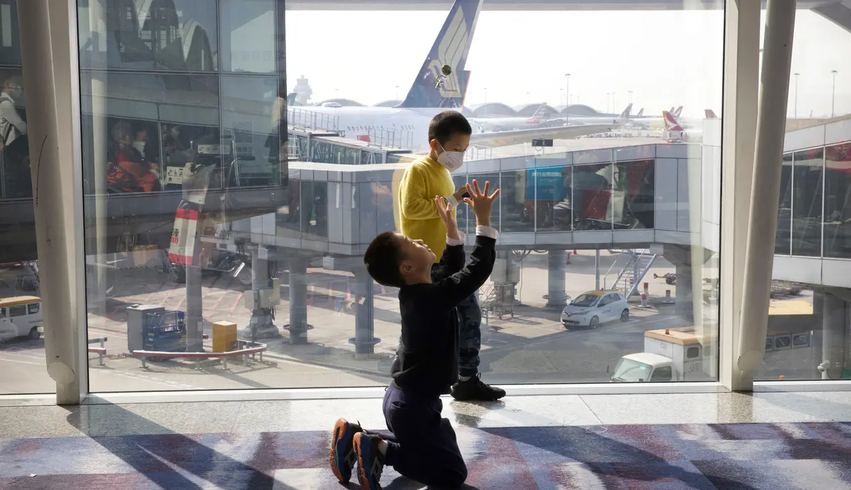 Seorang anak yang mengenakan masker bermain dengan anak laki-laki lain di Bandara Internasional Hong Kong di Hong Kong, Selasa (21/1/2020). Masker terjual habis dan pemeriksaan suhu di bandara dan stasiun kereta api menjadi norma baru di China menyusul merebaknya wabah virus corona. (AP/Ng Han Guan)