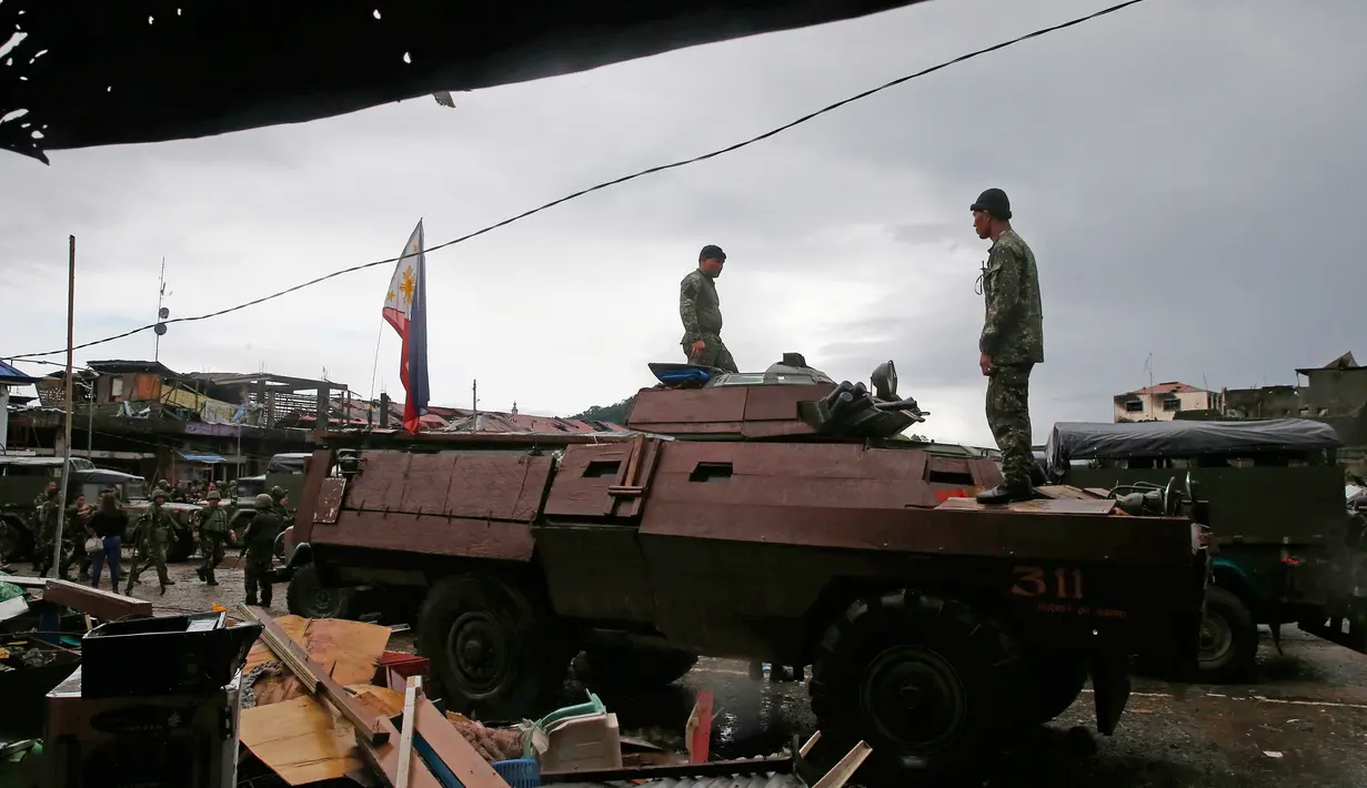 Dua tentara Filipina berdiri diatas tank usai menguasai kota Marawi dari tentara militan, Filipina (17/10). Duterte mendeklarasikan Kota Marawi telah terbebas dari kelompok militan Maute yang berafiliasi dengan ISIS. (AP Photo/Bullit Marquez)