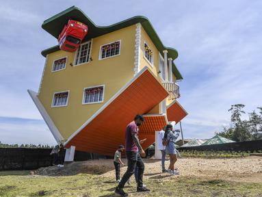 Orang-orang berjalan di luar rumah terbalik, di Guatavita, dekat Bogota, pada 29 Januari 2022. Rumah itu dirancang oleh pemiliknya, Fritz Schall dari Austria, yang tinggal di Kolombia. (Juan BARRETO / AFP)