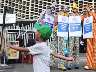 Tiga seniman egrang membawa poster Kampanye Aman Untuk Anak pada acara Deklarasi Pemilu Ramah Anak di Gedung Bawaslu, Jakarta, Minggu (17/3). KPU melarang anak-anak untuk terlibat dalam aktivitas kampanye politik. (Liputan6.com/Herman Zakharia)