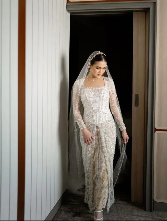 Sampai di hari H pemberkatan, Chen Giovani tampil elegan mengenakan kebaya panjang berwarna putih gading lansiran Myrna Myura. [IG/fcgweddings/myrnamyura]