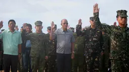 Menteri Pertahanan Delfin Lorenzana bersama Tentara Filipina saat mengikuti upacara pengibaran bendera di Pulau Thitu, Kepulauan Spratly, Laut China Selatan, Jumat (21/4). (AP Photo / Bullit Marquez)