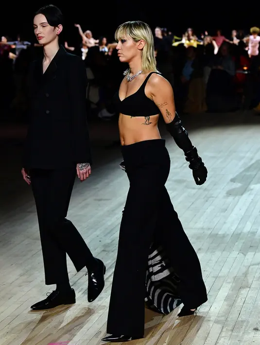 Miley Cyrus (kanan) berjalan di catwalk untuk show Marc Jacobs Fall 2020 selama New York Fashion Week di New York City, Rabu (12/2/2020). Miley Cyrus bergabung dengan sejumlah model di runway termasuk, Gigi Hadid dan adiknya, Bella Hadid serta Kaia Gerber. (Slaven Vlasic/Getty Images/AFP)