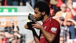 Penyerang Liverpool, Mohamed Salah, mencium trofi Sepatu Emas Premier League usai laga melawan Brighton & Hove Albion di Stadion Anfield, Minggu (13/5/2018). Salah menjadi top scorer Premier League musim ini dengan raihan 32 gol. (AFP/Paul Ellis)