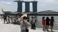 Seorang pengunjung, yang mengenakan masker pelindung di tengah kekhawatiran tentang penyebaran Virus Corona COVID-19, berjalan di sepanjang Merlion Park di Singapura pada 17 Februari 2020. (Roslan RAHMAN / AFP)