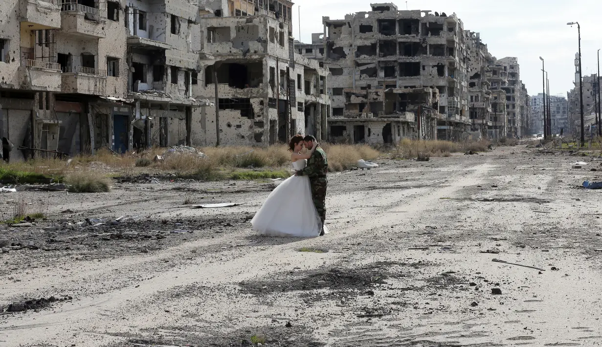 Pengantin baru, Nada Merhi (18) dan Hassan Youssef (27) menjalani sesi foto di kota Homs yang jadi medan perang di Suriah, 5 Februari 2016. Foto ini seolah bukti meski di tengah kehancuran, hidup terus berlalu dan harapan akan terus ada. (JOSEPH EID/AFP)