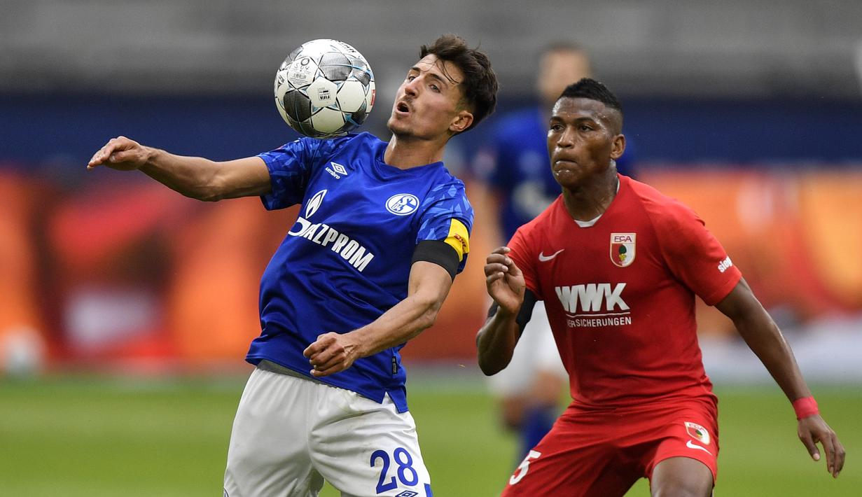 Pemain Augsburg, Carlos Gruezo, berebut bola dengan Schalke 04, Alessandro Schoepf, pada laga Bundesliga di Veltins-Arena, Minggu (24/5/2020). Augsburg menang dengan skor 3-0 atas Schalke 04. (AP/Martin Meissner)