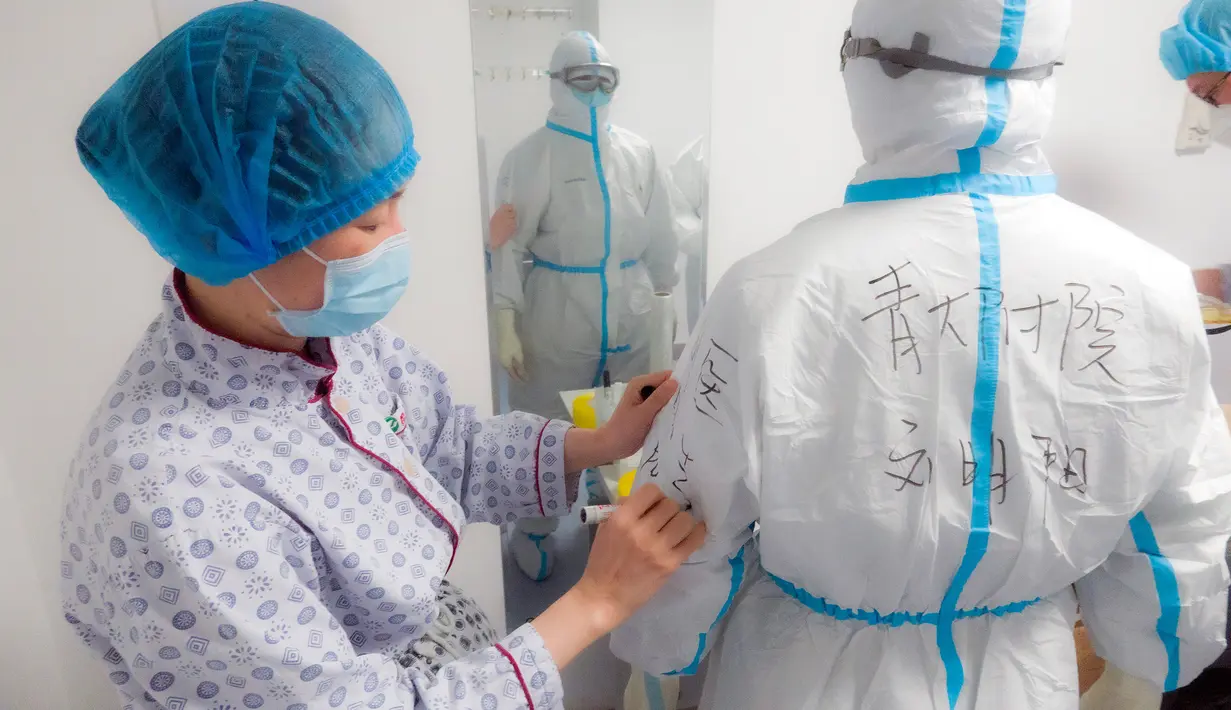 Petugas medis Rumah Sakit Afiliasi Universitas Qingdao memeriksa baju pelindung rekannya di Rumah Sakit Tongji cabang Guanggu di Wuhan, 20 Februari 2020. Beberapa langkah pencegahan dilakukan secara ketat selama dan sesudah jam kerja oleh pekerja medis untuk melawan virus corona. (Xinhua/Cai Yang)