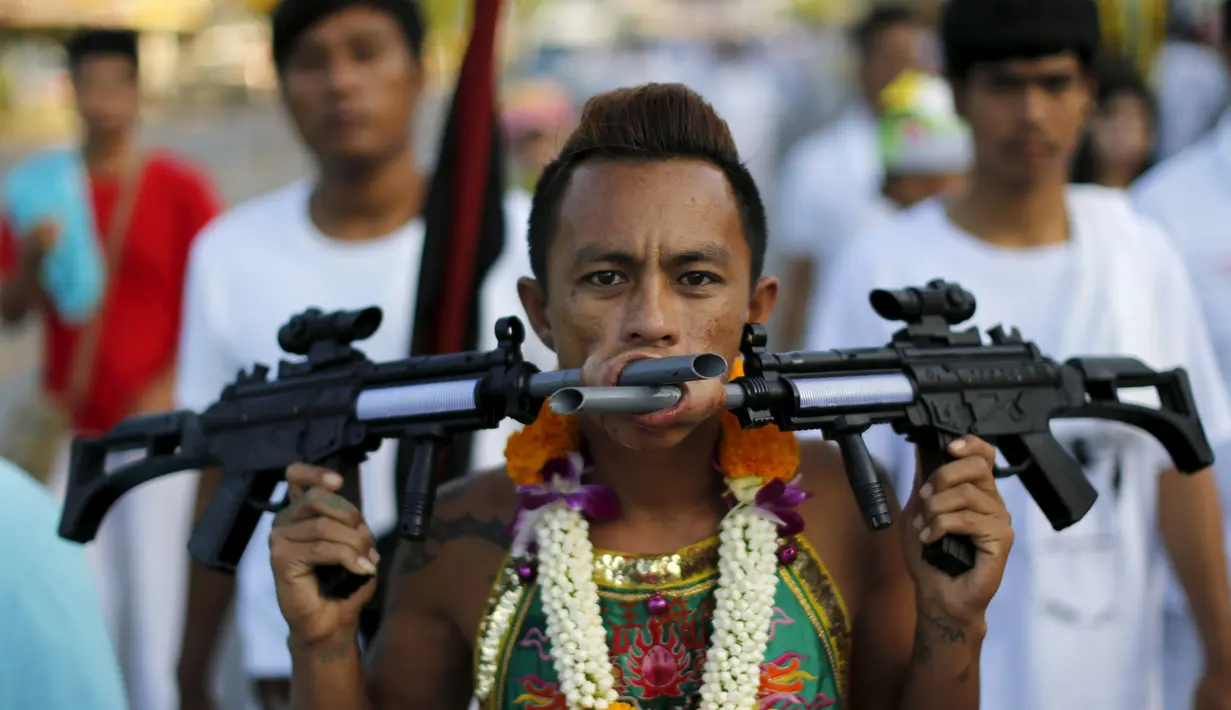Seorang pemuja dari Kuil Samkong menusukkan senjata ke pipi saat memeriahkan festival vegetarian di Phuket, Thailand (17/10/2015). Festival ini menampilkan aksi ekstrem pemuja dengan menusukkan benda tajam ke wajah. (REUTERS/Jorge Silva)