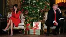Presiden AS Donald Trump dan istrinya, Melania Trump berbicara di telepon dengan anak-anak saat mereka mengikuti NORAD Tracks Santa di Palm Beach, AS (24/12). NORAD Tracks Santa adalah acara Natal melacak posisi Sinterklas. (AP Photo/Carolyn Kaster)