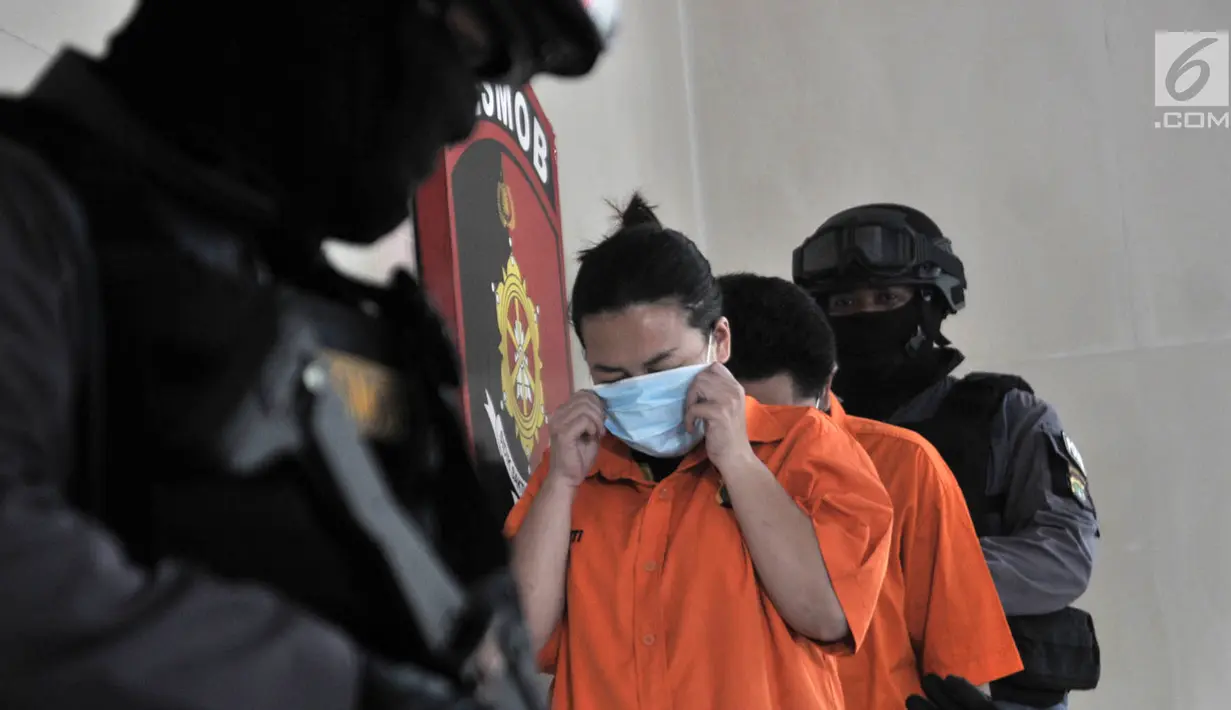 Polisi mengawal dua tersangka kasus prostitusi online di Apartemen Kalibata City, Jakarta, Minggu (6/5). Polisi menyita barang bukti berupa hp, uang tunai, kondom, kartu akses apartemen, dan krim pelembut. (Merdeka.com/Iqbal Nugroho)