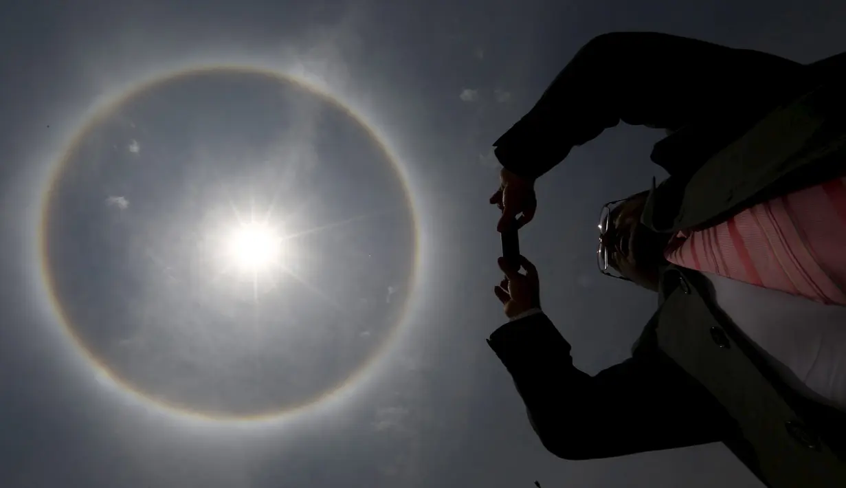 Seorang pria mengambil gambar 'Halo Matahari' di langit Mexico City, Meksiko, Kamis (21/5/2015). Menurut ahli meteorologi, fenomena cuaca menciptakan pelangi mengelilingi matahari dan dibentuk oleh refleksi dari kristal es. (REUTERS/Edgard Garrido)