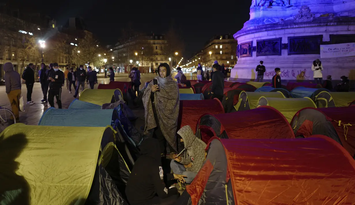 Aktivitas para migran di tenda yang mereka dirikan di Republic square, pusat kota Paris, pada Kamis (25/3/2021). Hampir 400 tenda didirikan di alun-aun tersebut untuk menarik perhatian atas kondisi kehidupan mereka dan menuntut akomodasi. (AP Photo/Rafael Yaghobzadeh)