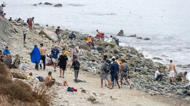 Sejumlah orang berjalan di pantai saat berusaha menyeberang dari Fnideq, Maroko utara, menuju Ceuta, wilayah Spanyol di Afrika Utara, Jumat (31/7/2026).