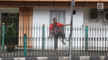Penumpang melompati pagar pembatas untuk keluar dari Stasiun Cikini di Jakarta, Jumat (22/3). Jauhnya akses pintu masuk dan keluar stasiun menyebabkan sebagian orang mempersingkat waktu dengan melompat pagar pembatas. (Liputan6.com/Immanuel Antonius)