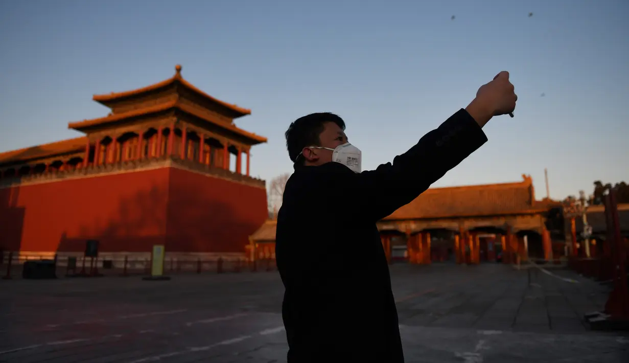 Seorang pria berswafoto di luar Kota Terlarang yang ditutup di Beijing pada Selasa (4/2/2020). Mencegah korban virus corona bertambah, China menutup  banyak destinasi wisata termasuk Kota Terlarang yang ditutup untuk kunjungan wisatawan sejak 24 Januari 2020 lalu. (GREG BAKER/AFP)