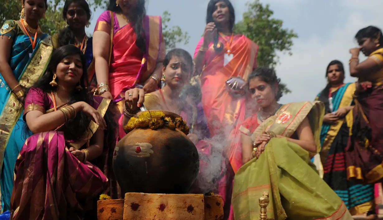 Para wanita India mempersiapkan pongal saat mengikuti kegiatan dalam perayaan festival panen Tamil sebuah perguruan tinggi di Chennai, India (11/1). (AFP Photo/Arun Sankar)