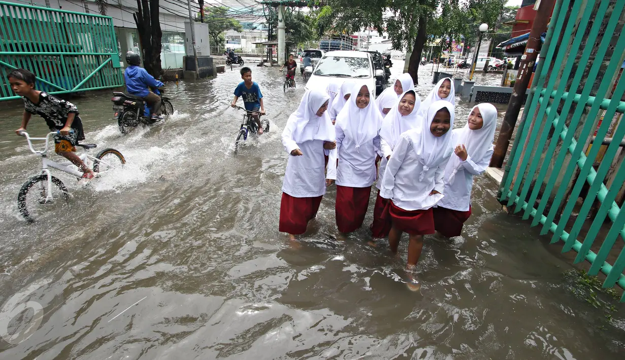 Sejumlah anak berusaha menerobos banjir yang merendam Jalan Panjang, Jakarta Barat, Jumat (26/2). Hujan yang mengguyur wilayah Jakarta membuat sejumlah titik terendam banjir dengan ketinggian sekitar 20 cm hingga 1 meter. (Liputan6.com/ Immanuel Antonius)