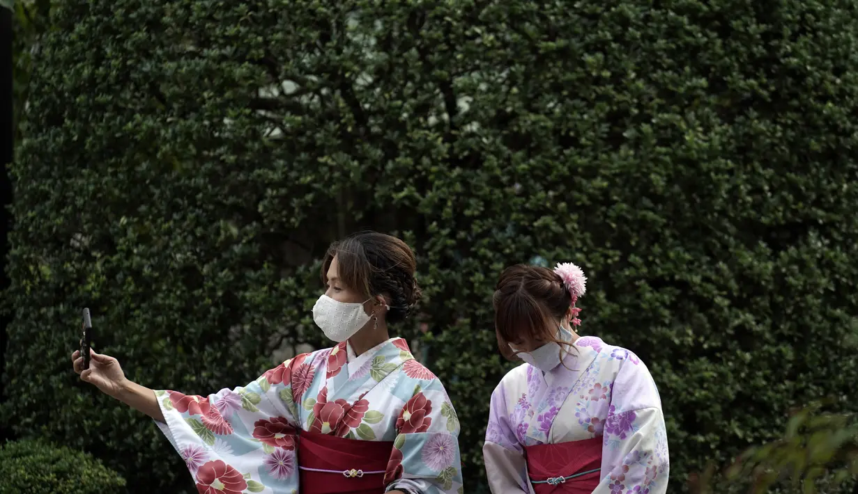 Pengunjung dengan masker pelindung untuk membantu mencegah penyebaran virus corona berfoto selfie di pusat perbelanjaan di distrik Asakusa di Tokyo, Selasa (29/9/2020). kota Jepang mengonfirmasi lebih dari 200 kasus virus corona pada hari Selasa. (AP Photo/Eugene Hoshiko)