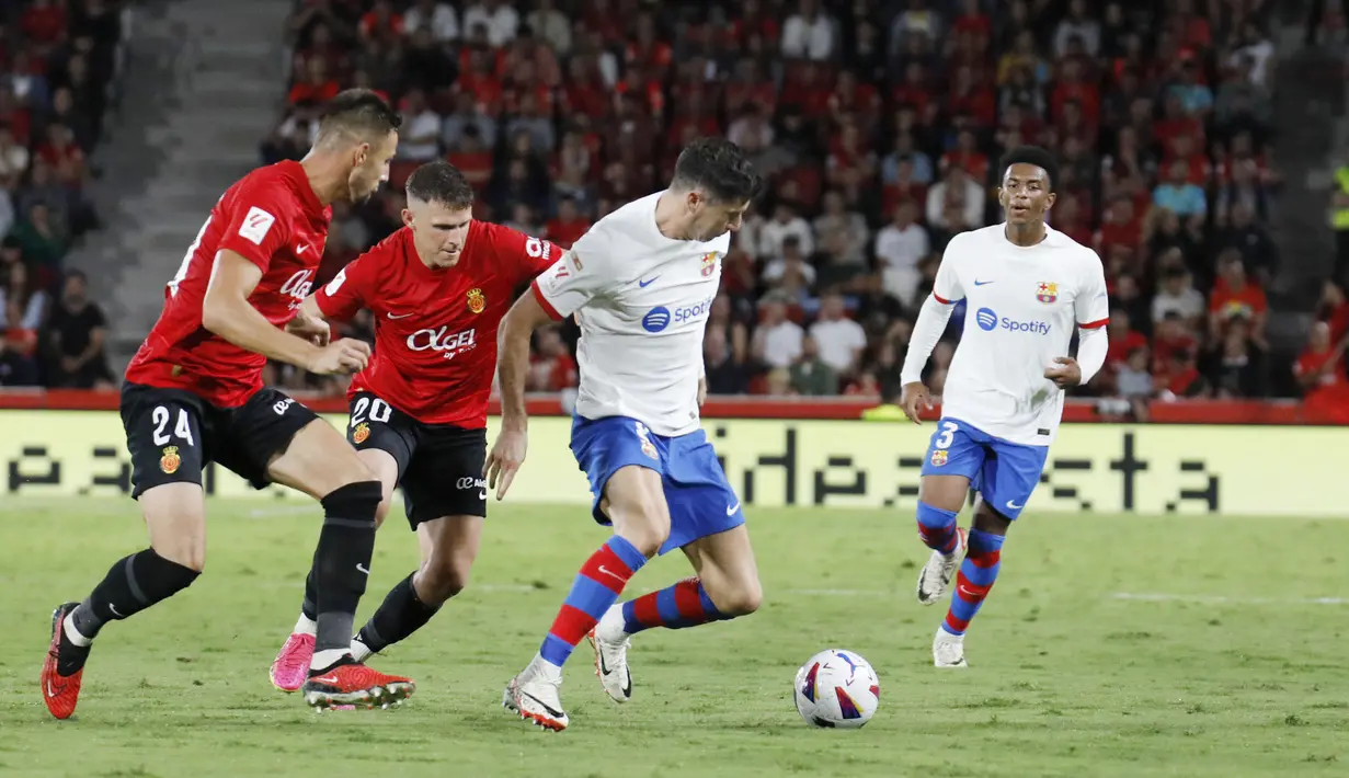 Pemain Barcelona, Robert Lewandowski, berusaha melewati pemain Real Mallorca pada laga pekan ke-7 La Liga 2023/2024, di Stadion Mallorca Son Moix Rabu (27/9/2023). Kedua tim bermain sama kuat 2-2. (AP Photo/Francisco Ubilla)