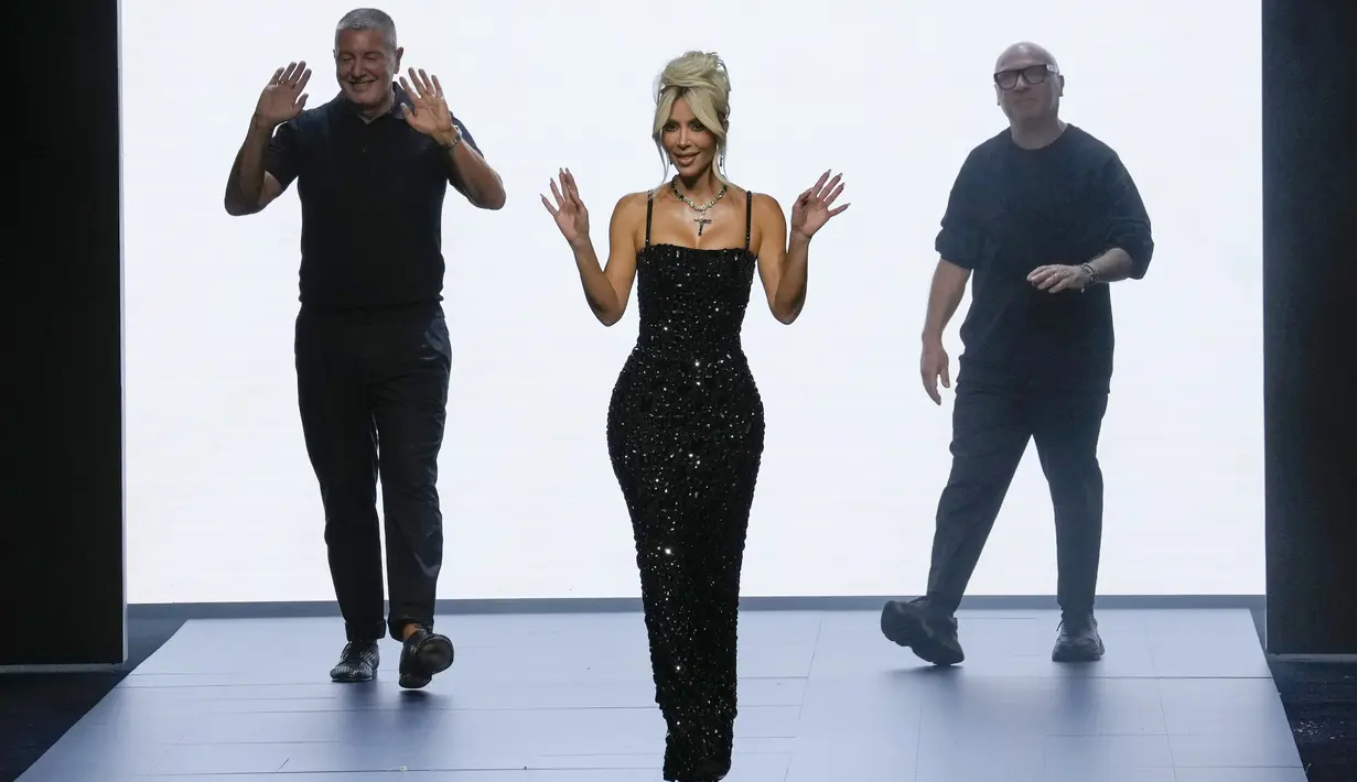 Kim Kardashian bersama Domenico Dolcedan Stefano Gabbana di akhir peragaan busana wanita Dolce & Gabbana Spring Summer 2023 di Milan, Italia, 24 September 2022. Dress yang dikenakan Kim dipasangkan dengan boots heels hitam dan kalung berukuran besar dengan simbol salib di bagian tengahnya.  (AP Photo/Antonio Calanni)