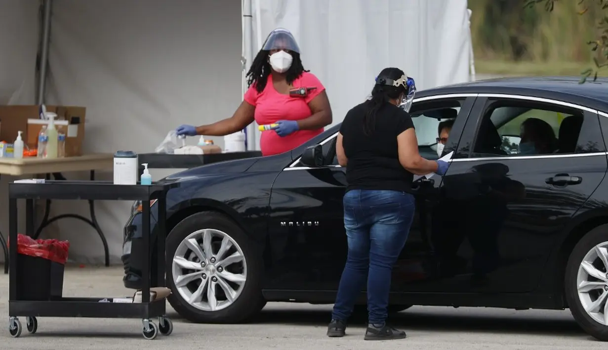 Petugas kesehatan memeriksa warga sebelum mengarahkan ke area vaksinasi COVID-19 drive-thru di Vista View Park, Davie, Florida, Amerika Serikat, 4 Januari 2021. Lokasi vaksinasi COVID-19 drive-thru tersebut disiapkan untuk penduduk Broward yang berusia 65 tahun ke atas. (Joe Raedle/Getty Images/AFP)