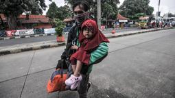 Pemudik membawa barang mereka seusai turun dari bus antarkota antarprovinsi (AKAP) di Terminal Kampung Rambutan, Jakarta, Minggu (23/5/2021). Hingga sore ini pemudik dari kota di Jawa Barat, Tengah, Timur, dan Sumatera terus berdatangan di Terminal Kampung Rambutan. (merdeka.com/Iqbal S Nugroho)