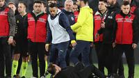 Pelatih Galatasaray, Okan Buruk, bawah, tergeletak di tanah setelah manajer Fenerbahce Jose Mourinho, tengah, memegang hidungnya di akhir pertandingan sepak bola perempat final Piala Turki antara Fenerbahce dan Galatasaray di stadion Ulker, di Istanbul, Kamis dini hari WIB (3-4-2025). (Foto Murat Akbas/Dia via AP)