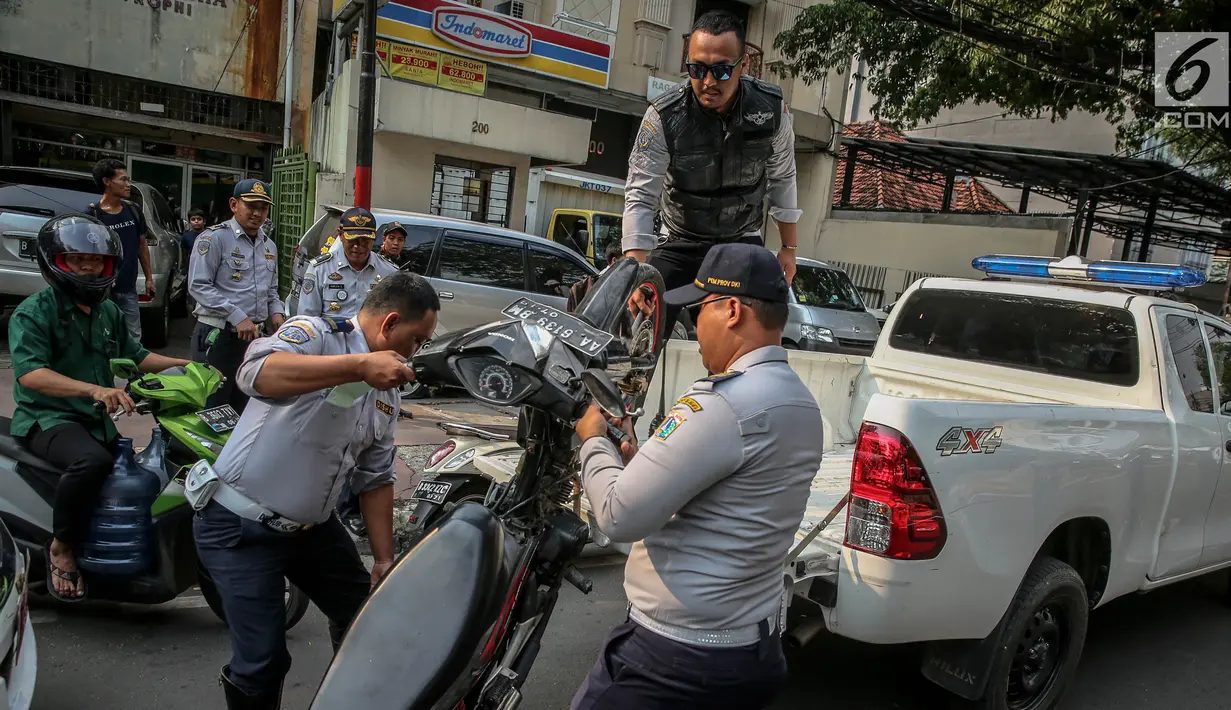 Petugas Dishub mengangkut sepeda motor ke atas truk selama penertiban parkir liar di trotoar kawasan KH Wahid Hasyim, Jakarta, Selasa (1/8). Penertiban dalam rangka Bulan Patuh Trotoar itu untuk mengembalikan fungsi trotoar. (Liputan6.com/Faizal Fanani)
