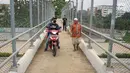 Pengendara sepeda motor melintasi JPO yang melintang di atas Tol Cijago Seksi II di Depok, Jawa Barat, Rabu (15/5). Meskipun berbahaya, namun curamnya akses JPO tidak menjadi penghalang bagi sebagian pemotor untuk menyeberang agar dapat memersingkat waktu tempuh. (Liputan6.com/immanuel Antonius)