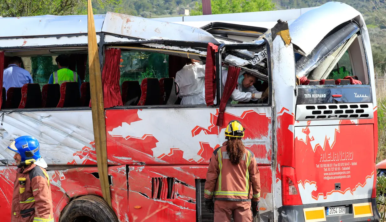 Petugas menyelidiki sebuah bus berisi mahasiswa asing yang mengalami kecelakaan di Jalan Raya AP7 dekat Kota Freginals, Spanyol, Minggu (20/3). Sedikitnya 13 penumpang tewas dalam insiden itu sementara puluhan lainnya luka-luka. (PAU Barrena/AFP)
