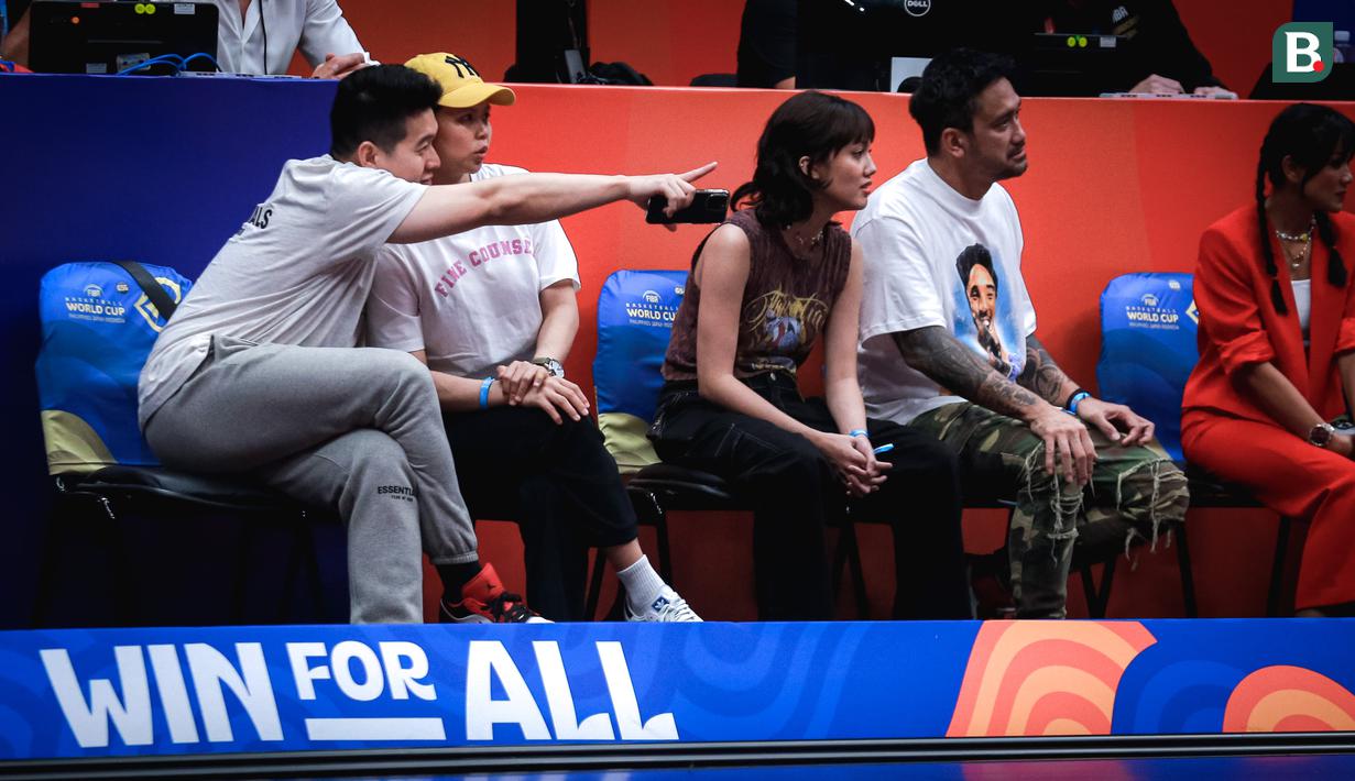 Mantan pebulu tangkis Indonesia, Greysia Polii (tengah kiri) bersama suaminya, Felix Djimin (kiri) duduk di samping selebritas Tora Sudiro (kanan) bersama putrinya, Azzahra Nabila Sudiro saat menyaksikan laga Grup H Piala Dunia FIBA 2023 antara Kanada melawan Prancis di Indonesia Arena, Senayan, Jakarta, Jumat (25/08/2023). (Bola.com/Bagaskara Lazuardi)
