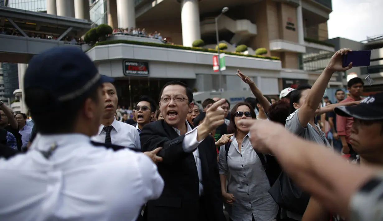 Seorang pengunjuk rasa pro-demokrasi (tegang) bersitegang dengan polisi dan massa anti-demokrasi di lokasi utama berlangsungnya aksi demonstasi di Admiralty, Hong Kong, (13/10/2014). (REUTERS/Carlos Barria)