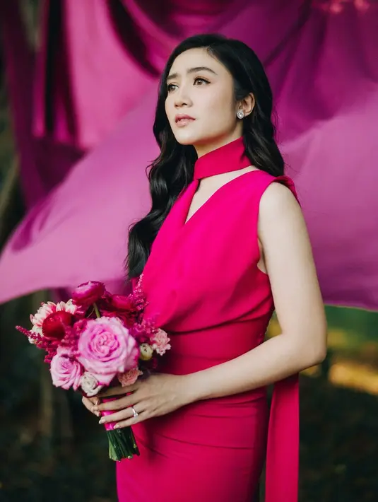 Gaun lansiran @pamelausanto.atelier itu hadir dengan detail kerah v-neck, tanpa lengan, dan selendang panjang hingga menyapu rumput yang memberikan sentuhan dramatis. [@terralogical @leurafilm].