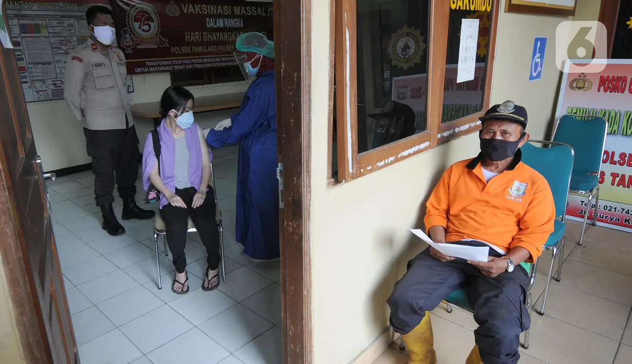 Seorang pria (kanan) menunggu untuk menerima vaksin covid-19 di Polsek Pamulang, Tangsel, Kamis (1/7/2021). Sebanyak 10 ribu dosis vaksin untuk warga 18 tahun ke atas dibagikan di wilayah Polres Tangerang Selatan dalam rangka HUT Bhayangkara Ke-75 yang jatuh pada hari ini. (merdeka.com/Arie Basuki)