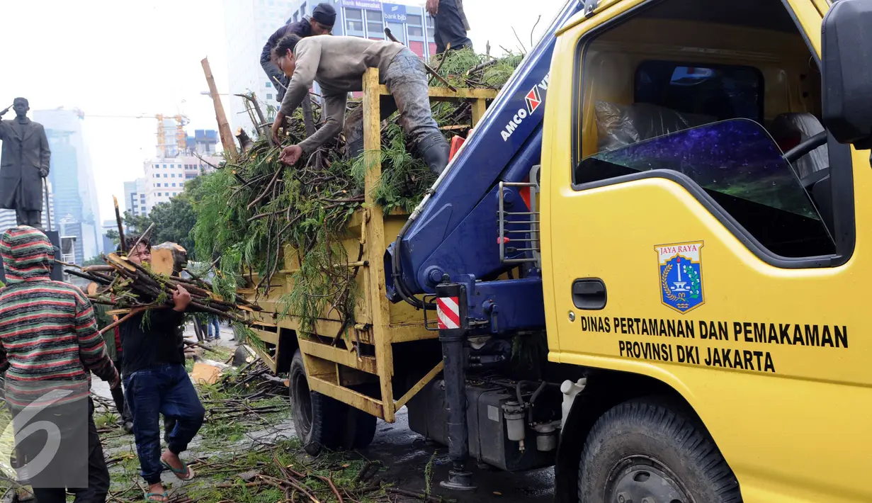 Petugas Dinas Pertamanan dan Pemakaman Provinsi DKI Jakarta mengangkut batang pohon besar yang tumbang ke atas truk  di Jakarta, Senin (1/2). Pohon tumbang yang terjadi saat hujan deras mengakibatkan kemacetan panjang. (Liputan6.com/Helmi Afandi)
