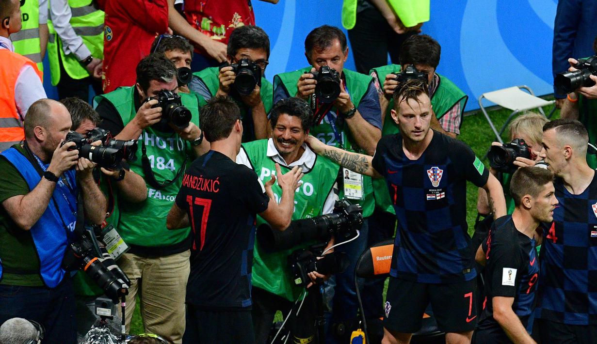 Mario Mandzukic (kiri) dan Ivan Rakitic menyapa fotografer AFP, Yuri Cortez (tengah) usai merayakan gol pada semifinal Piala Dunia 2018 di Luzhniki Stadium, Moskow, (11/7/2018). Yuri jatuh saat perayaan gol skuat Vatreni. (AFP/Mladen Antonov)