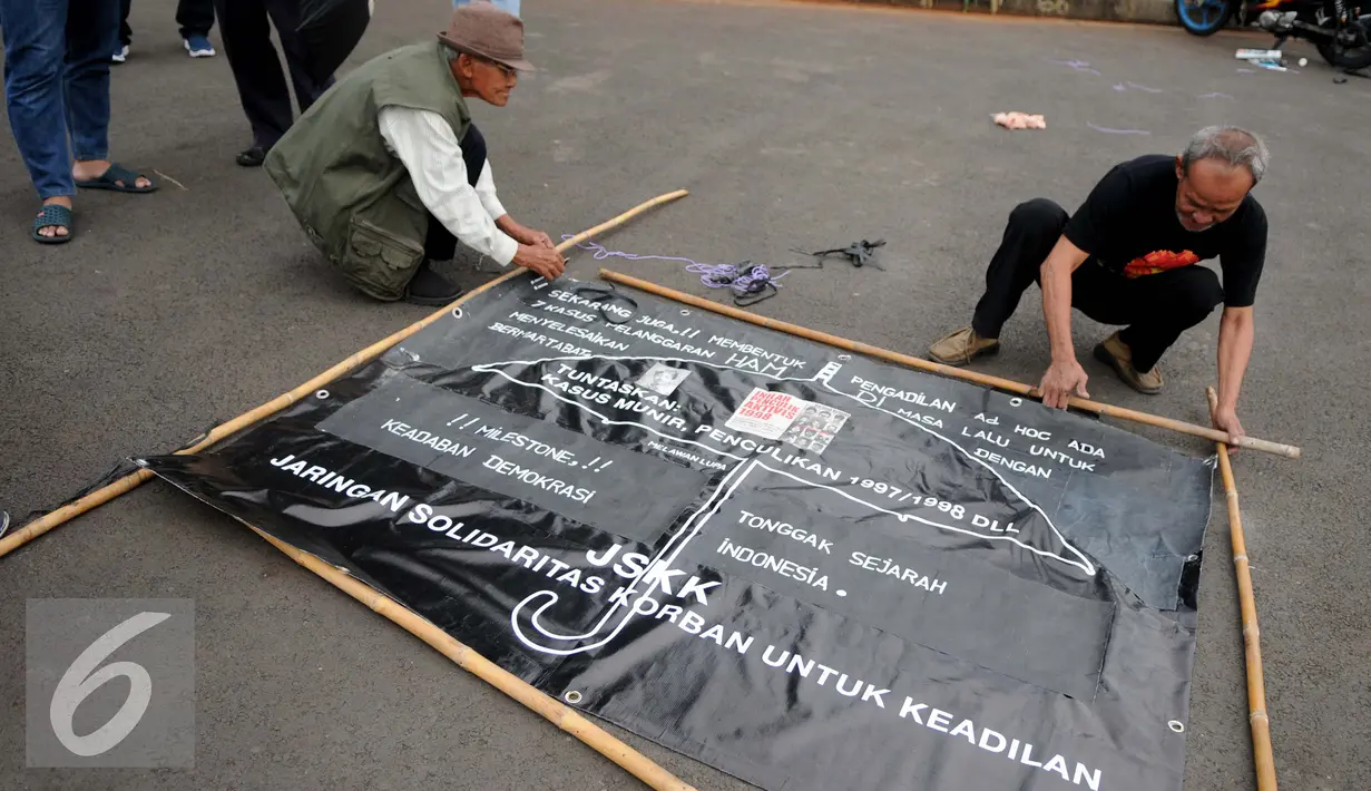 Aktivis Jaringan Solidaritas Korban memasang spanduk saat menggelar aksi Kamisan di depan Istana Merdeka, Jakarta, Kamis (29/12). Dalam aksi dipengujung tahun 2016 mereka menuntut pemerintah menyelesaikan berbagai kasus HAM. (Liputan6.com/Gempur M Surya)