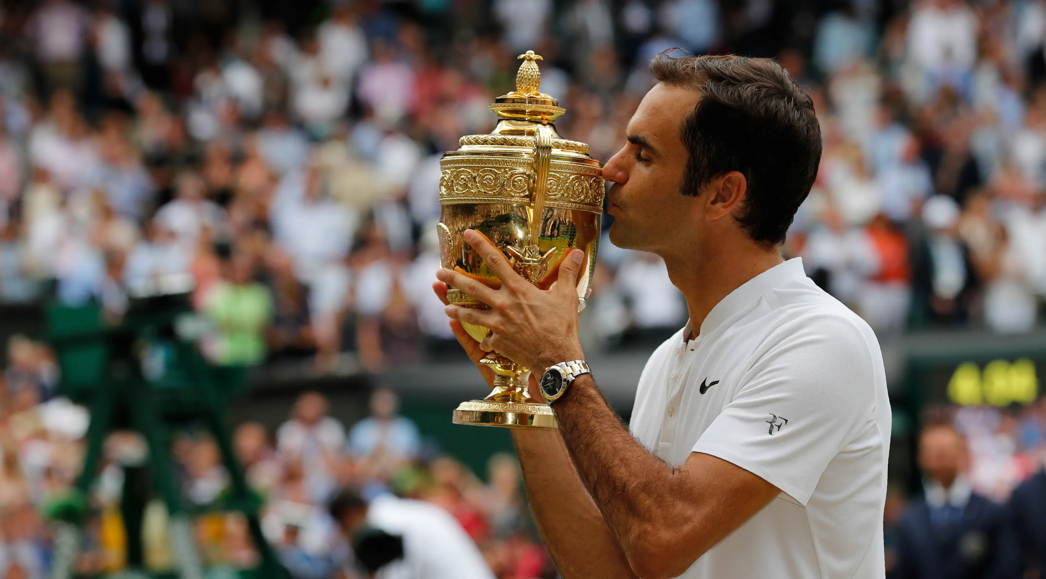 Petenis Swiss, Roger Federer mencium trofi setelah melawan petenis Kroasia, Marin Cilic pada pertandingan final tunggal putra Kejuaraan Wimbledon 2017 di Wimbledon, London. (16/07). Roger Federer menang 6-3, 6-1, 6-4. (AFP Photo / Adrian Dennis)