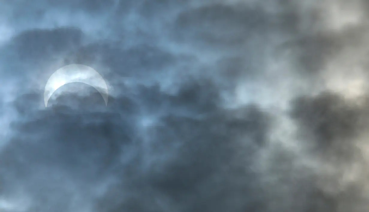 Gerhana Matahari Cincin Api muncul dari balik awan di atas Logan, Utah, Amerika Serikat, Sabtu (14/10/2023). Gerhana Matahari terjadi ketika bulan baru berada tepat di antara Bumi dan Matahari serta menjatuhkan bayangannya ke Bumi. (Eli Lucero/Herald Journal via AP)