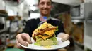 Koki Irlandia, Colin Kelly berpose dengan burger "Durty Donald" di restoran Durty Bird, Hanoi, Vietnam, 21 Februari 2019. Menu baru ini terinspirasi pertemuan puncak antara Presiden AS Donald Trump dan pemimpin Korut, Kim Jong-un. (Manan VATSYAYANA/AFP)