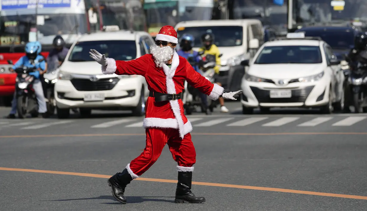 Petugas lalu lintas Filipina Ramiro Hinojas mengenakan kostum Sinterklas saat mengarahkan arus kendaraan di kota Pasay, Selasa, 5 Desember 2023. (AP Photo/Aaron Favila)