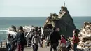 Warga dan turis menikmati cuaca musim dingin yang hangat saat berjalan di sepanjang garis pantai di Biarritz, Perancis (17/2). Kota ini terletak di region Aquitane, Departemen Pyrénées-Atlantiques. (AFP Photo/Iroz Gaizka)